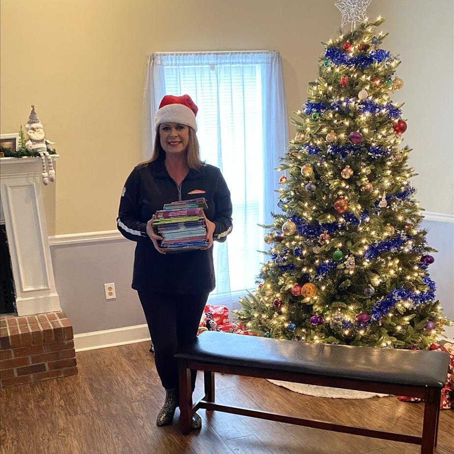 SERVPRO employee with donated books for children standing in front of decorated treetree